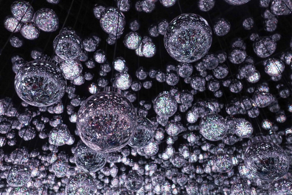 An image of a display in the teamLab Borderless (Azabudai Hills) showing hanging reflective orbs.
