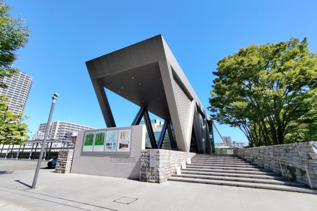 An image of The Museum of Contemporary Art Tokyo (MOT) exterior showing angular concrete entrance area from bellow.