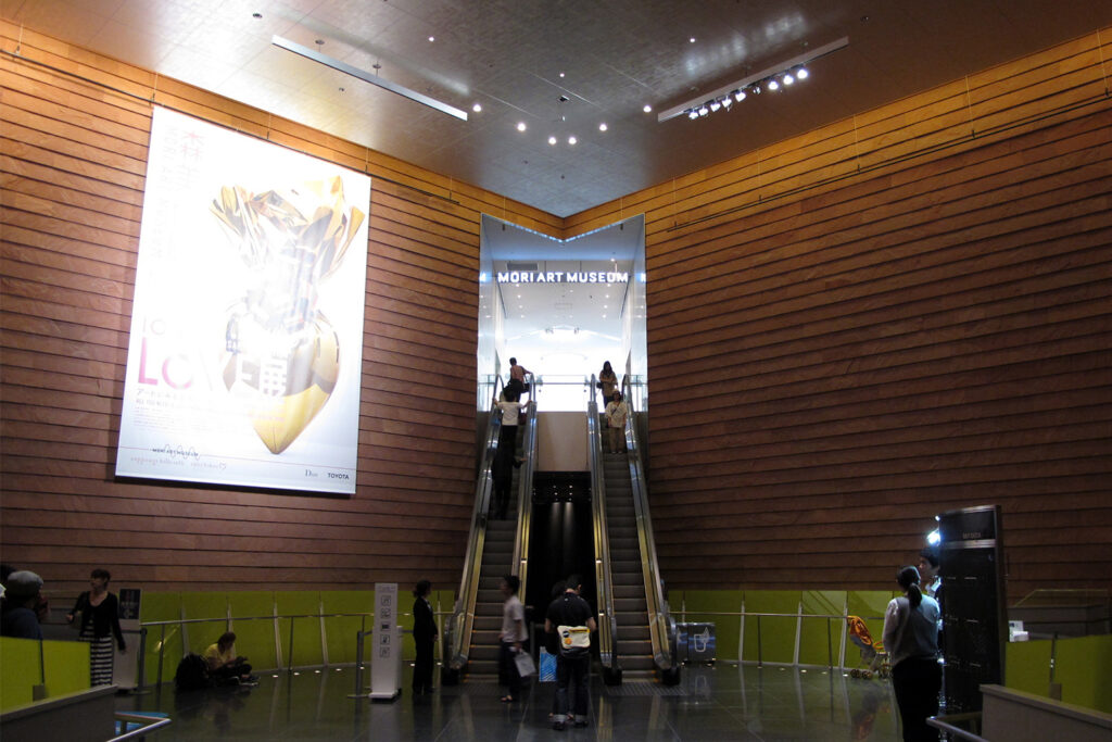 An image of the entrance to Mori Art Museum with escalators and wood paneling.