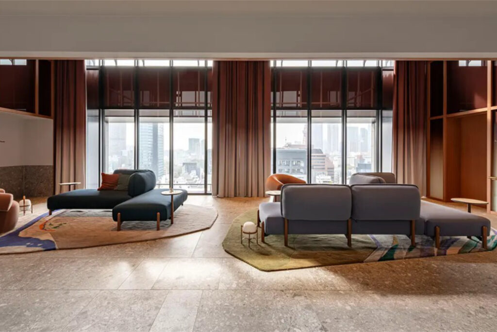 Upper-floor lounge at World Tower Residence with double-height windows, terracotta drapes and central Tokyo views
