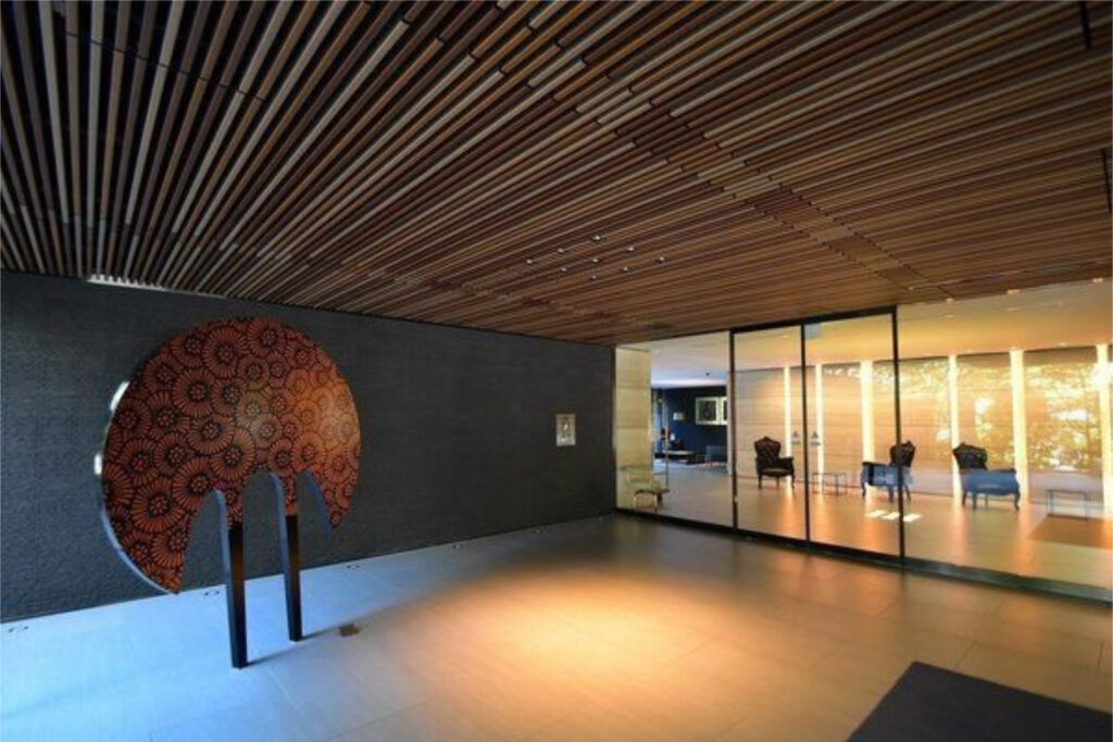 The Westminster Roppongi entrance hall with a slatted timber ceiling and circular patterned artwork on a dark stone wall