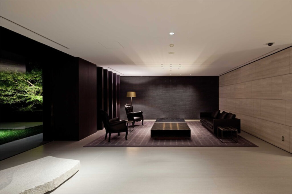 Residents' lounge at The Westminster Roppongi with dark leather seating and a lit Japanese garden beyond the window