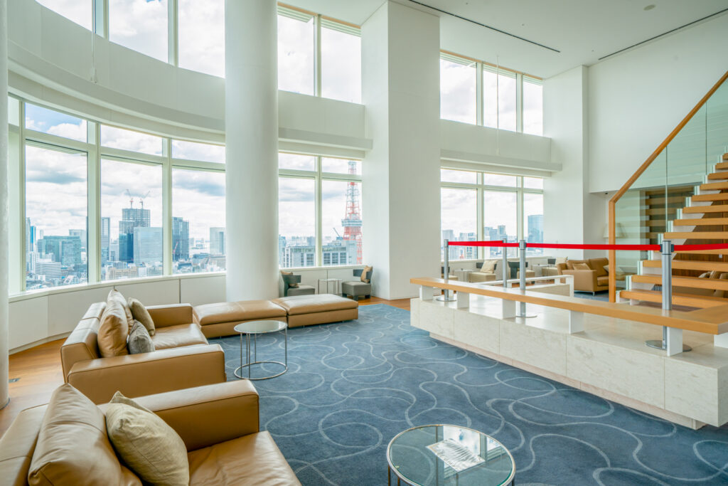View lounge at Ark Hills Sengokuyama Residence with double-height curved windows overlooking Tokyo Tower