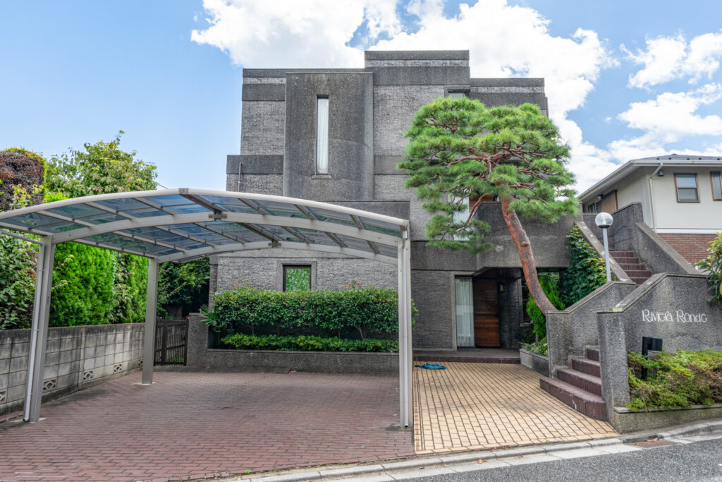 Two-storey stone-clad detached house in Oyamadai, Setagaya-ku, with a covered carport and private driveway.