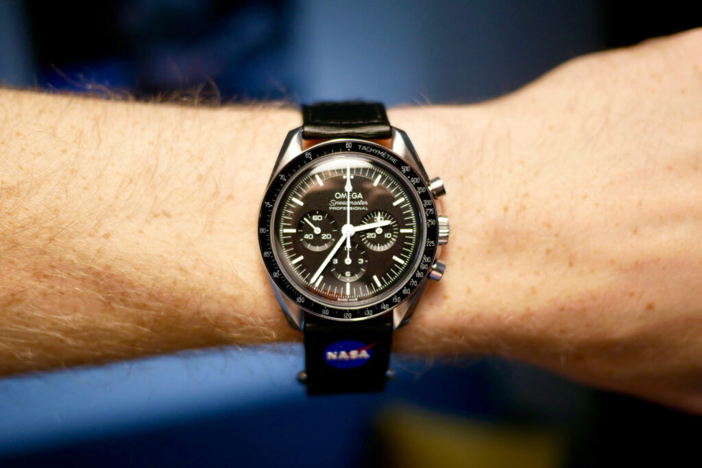 Omega Watch on a mans wrist. Black watch face on a leather strap
